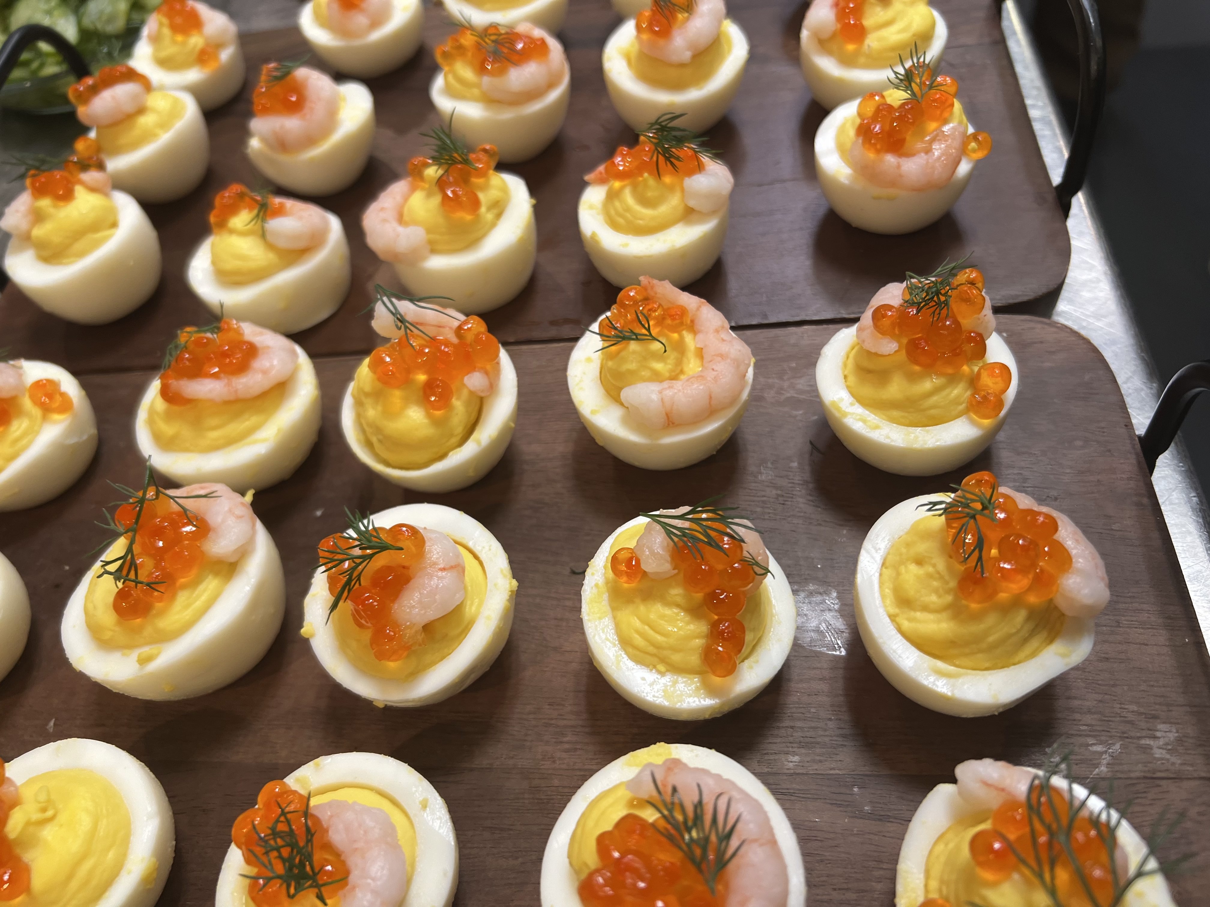 Tray of deviled eggs topped with small shrimp, red fish roe, and sprigs of dill.